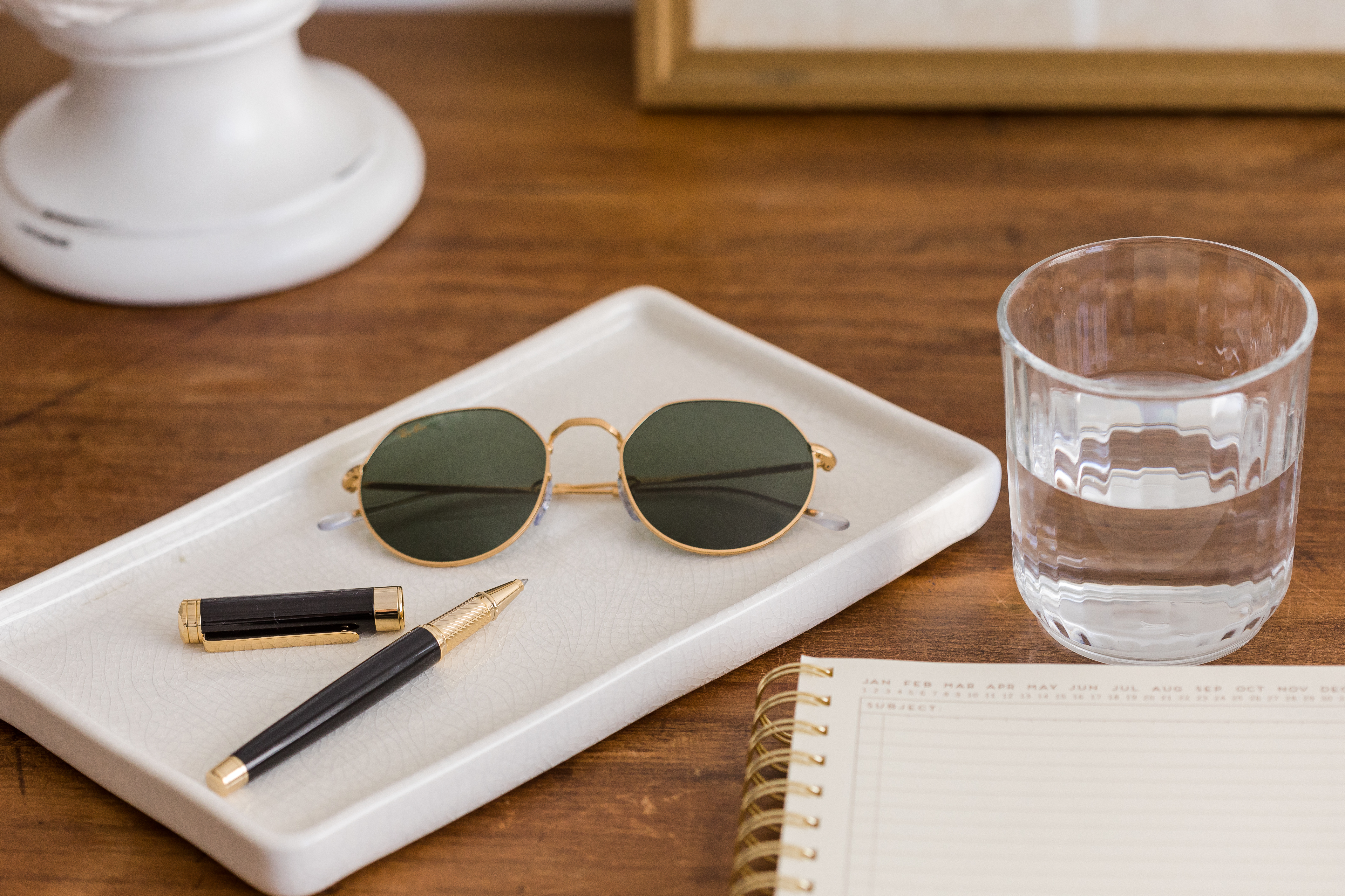 Notepad, pen, sunglasses and water on table—props for women investors exploring cryptocurrency.