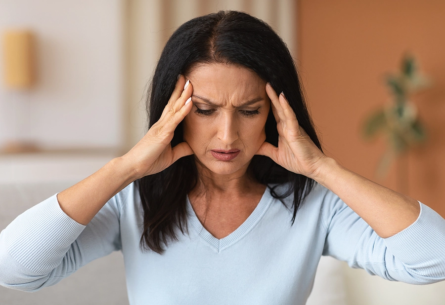 A woman holding her head in visible exhaustion—featured in the Curated Letter as a gateway to explore adrenal fatigue, decoding this controversial diagnosis with appropriate elegance and with scientific insight.