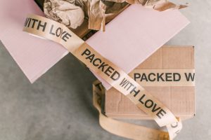 Curated Letter February–March 2023: a brown-paper package tied with a cream “packed with love” ribbon, with pale rose envelopes—quietly styled for elegant sophistication.