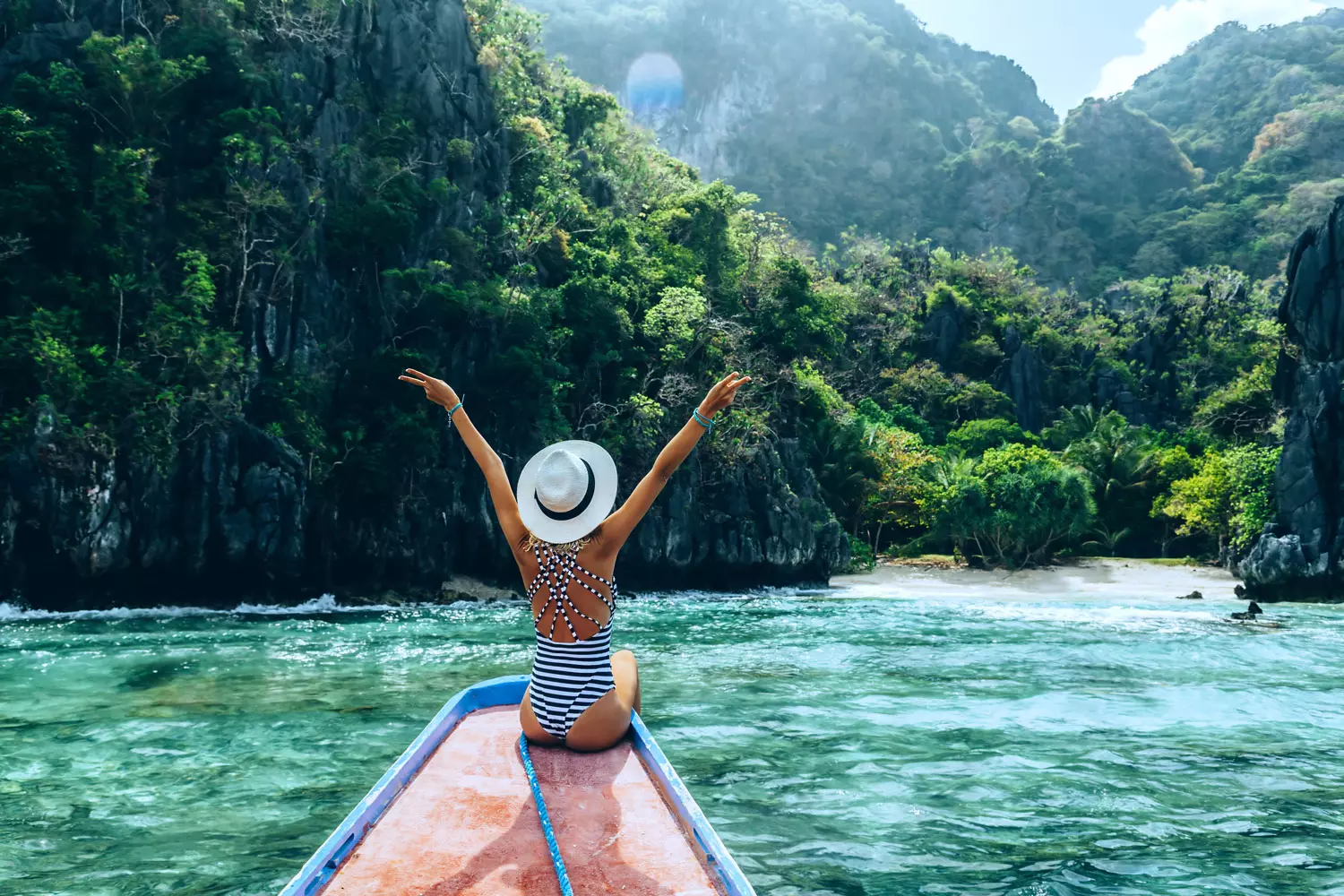 A woman sitting at a mountain lakeside overlooking a beautiful summer landscape at a mountain lake. The woman has her arms raised into the air, happy to have successfully secured her lifestyle for life by improving her financial savvy.