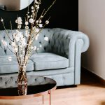 A duck-egg Chesterfield sofa and coffee table with flowers create an elegant, composed setting for a Women’s Guide on finding a Wealth Manager.