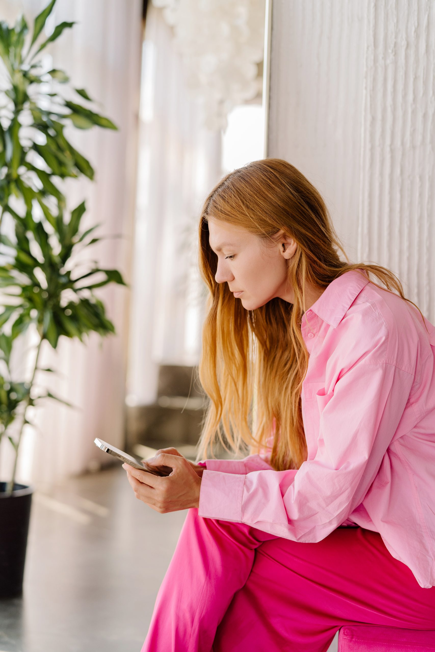 Woman wearing fuschia colored trousers with a pink shirt dialling in to her scheduled concierge chat to find out more about Invest!Elle´s mentoring, letters and the community