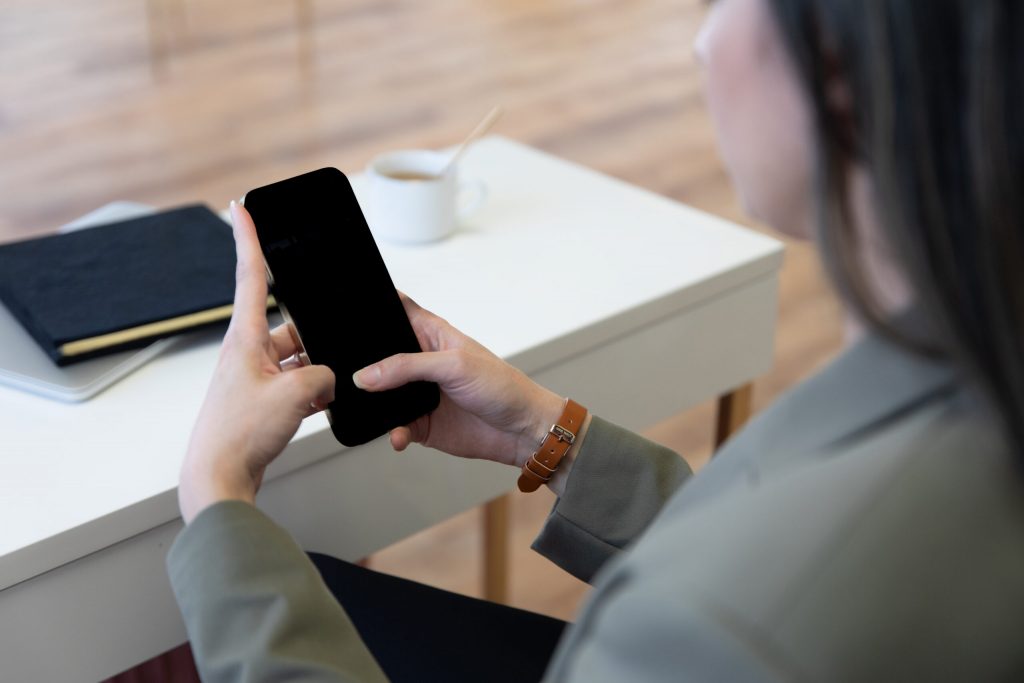 Woman with a grey jacket holding a mobile phone - ready to start her free concierge call
