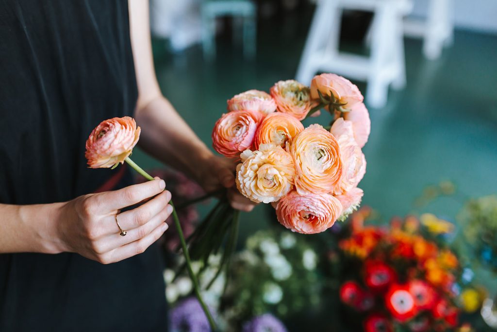Woman arranging flowers , the visible elegance and choice pof paech and pink colored flowers symboliza carefully curated letters.