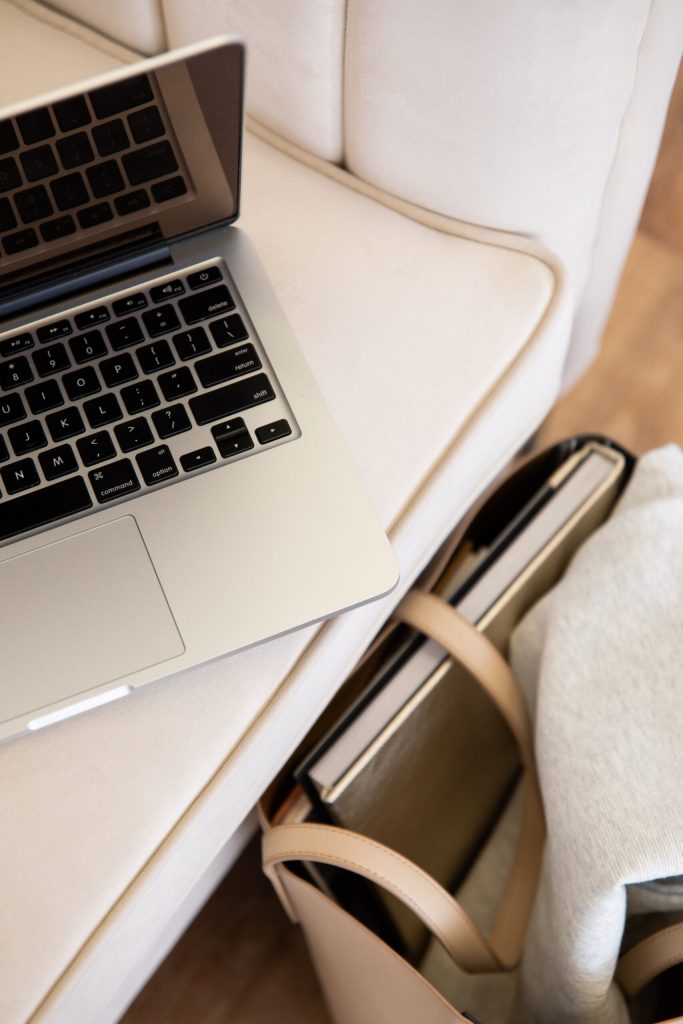 A desk with a laptop and a bag with a Notebook in hues of cream, taupe and beige, symbolising the serenity of financial savvy.