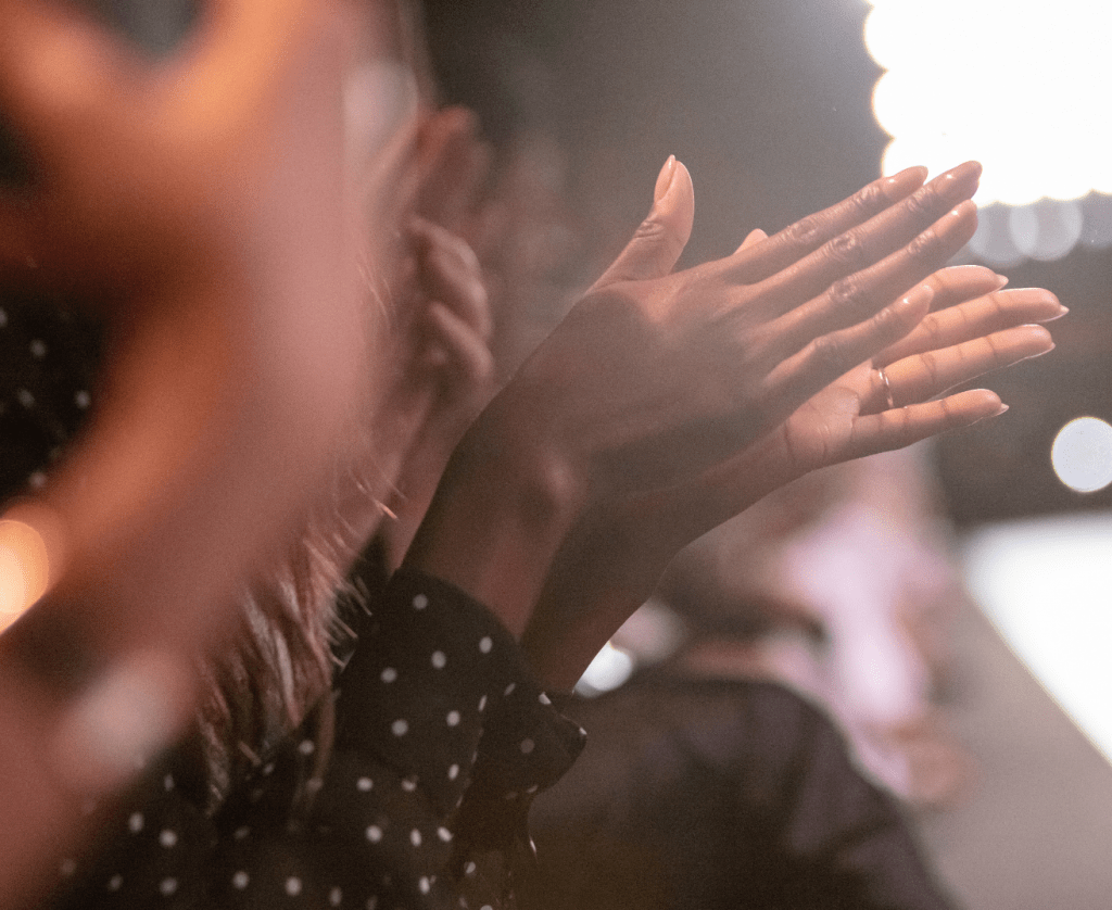 Women, members of the Capsule Community, clapping their hands, honouring the achievement of reaching the goal of financial savviness. The honoured friend is like them a memember of their peer society