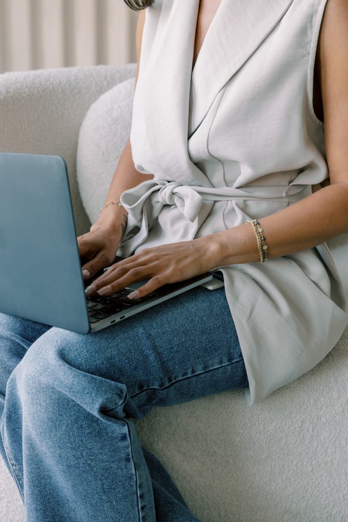 woman with a shortsleved vest and a laptop on her knees, registering to book her 120 minute complimentary mentoring session